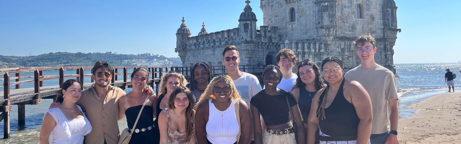 Group of Sage Corps students standing in front of castle located on beach in Lisbon, Portugal